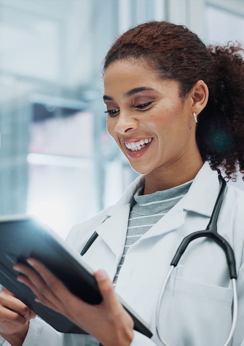 A smiling doctor reviewing notes on a tablet